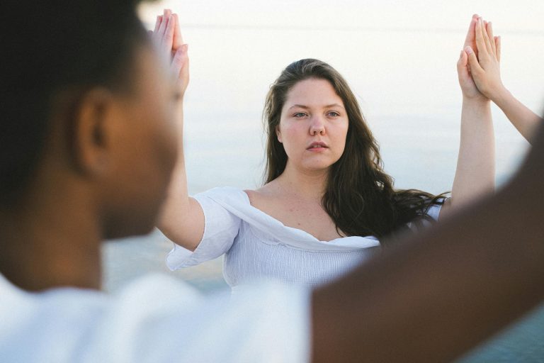 Two women engaging in a calming outdoor meditation session on a sunny day, promoting mindfulness and connection.